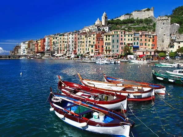 Holzboote im Hafen von Portovenere unterhalb einer Reihe hoher bunter Häuser